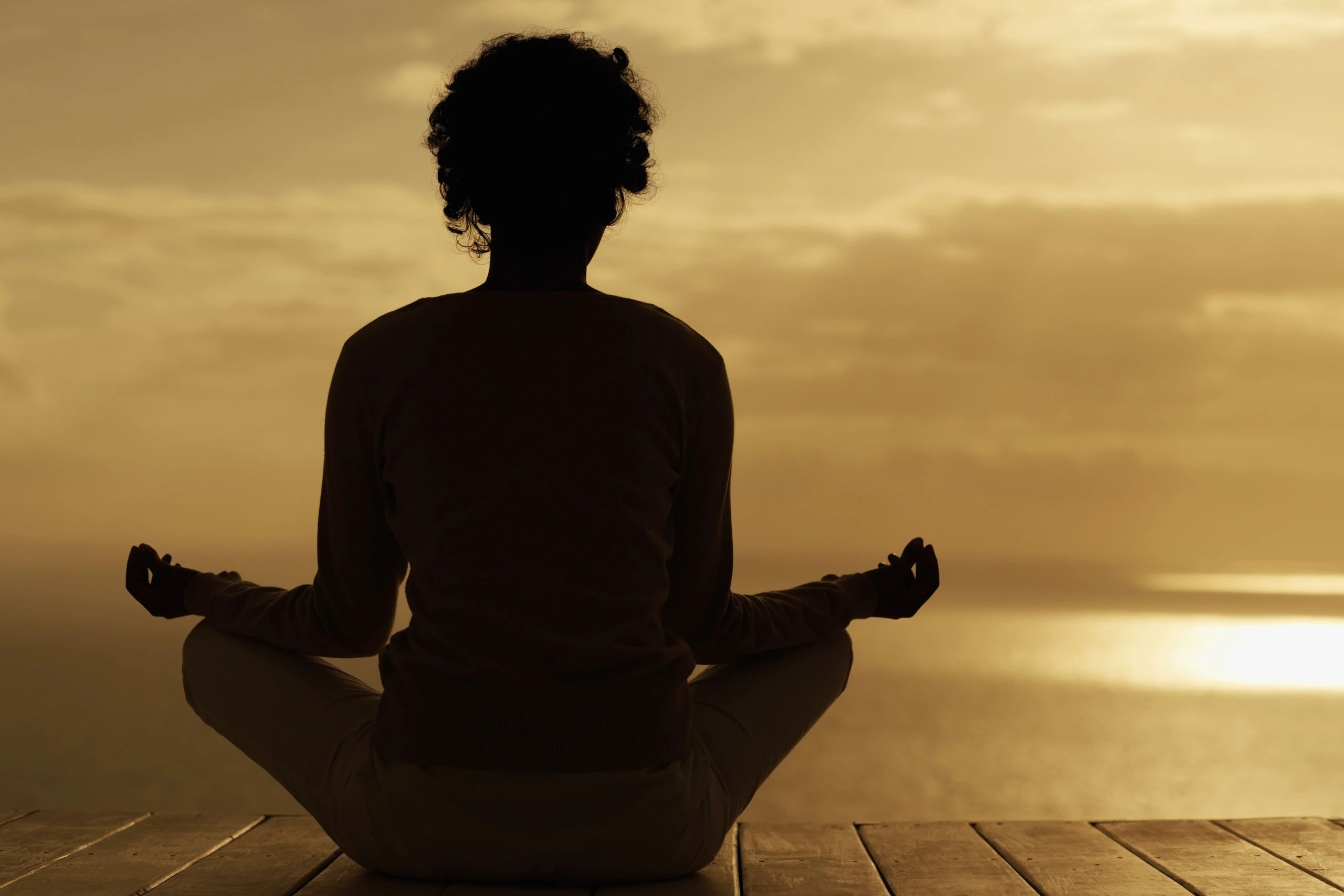 Silhouette of a woman meditating by the sea